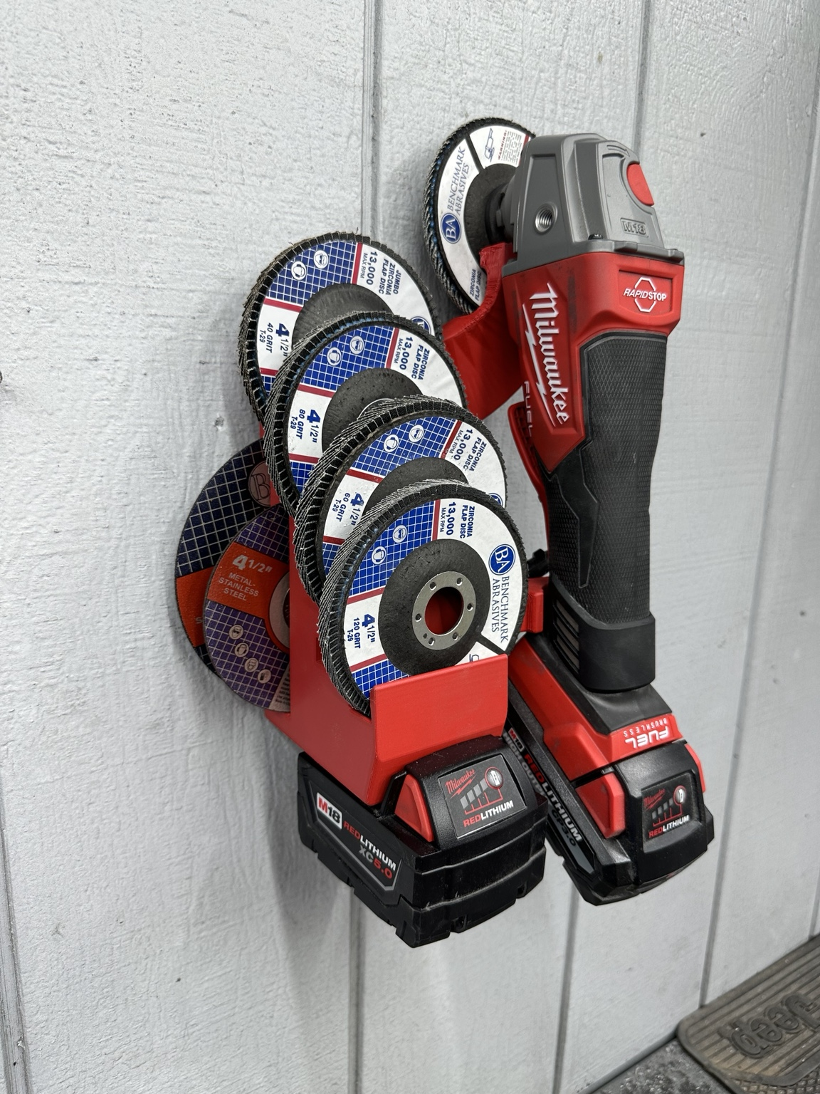 TBE Grinder Station with Milwaukee angle grinder, batteries, flap wheels and cutoff wheels mounted on a wall